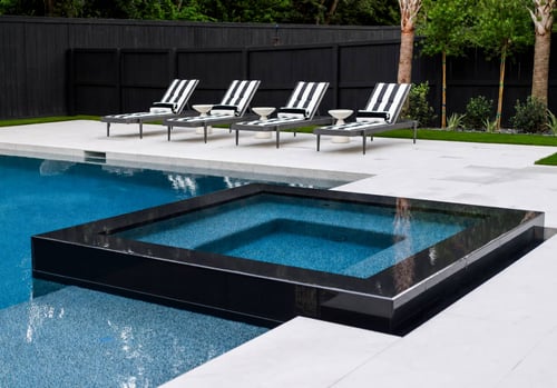 Modern raised spa with black tile exterior overlooking an inground pool