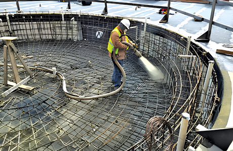 Blue Haven worker spraying gunite over steel rebar framework during pool construction