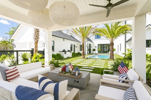 Modern covered patio decorated for a 4th of July pool party with American flag pillows and red, white, and blue florals.