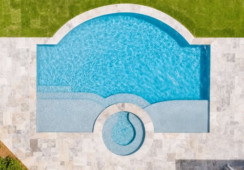 Aerial view of an inground pool with extended step bench seating and round spa