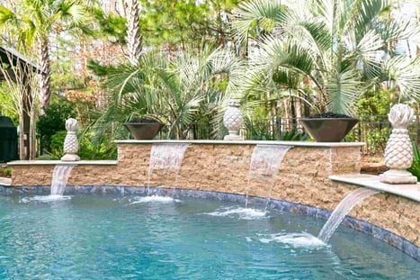 Raised wall waterfalls flowing into custom Blue Haven gunite swimming pool