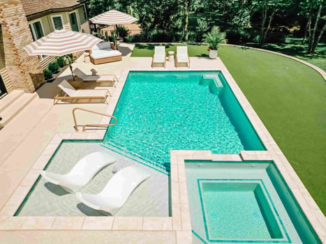 Blue Haven gunite pool tanning ledge with lounge chairs and adjacent spa