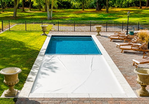 Automatic pool cover half closed over a rectangular inground pool