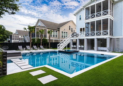 Modern backyard pool with tanning ledge and stepping stones behind a coastal home