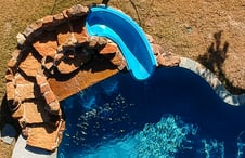 blue-slide-on-rock-waterfall-on-freeform-pool