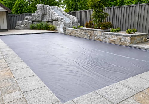Closed automatic pool cover protecting an inground pool and rock water slide