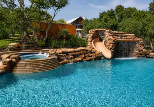 Custom inground pool with rock waterfall, slide, and raised spa built with pool financing