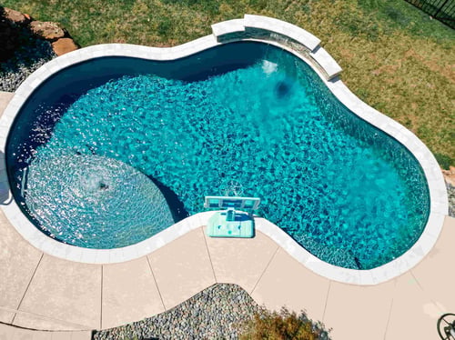 Custom gunite pool with deck jets, sheer descent waterfall, attached spa, and landscaped outdoor living area