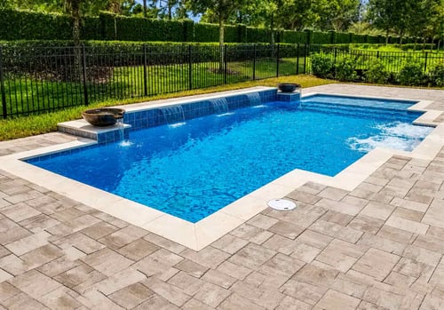 geometric-pool-bowl-waterfalls-blue-tile-paver-deck