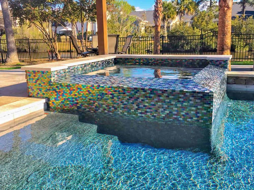 Raised gunite spa with custom iridescent glass mosaic tile finish