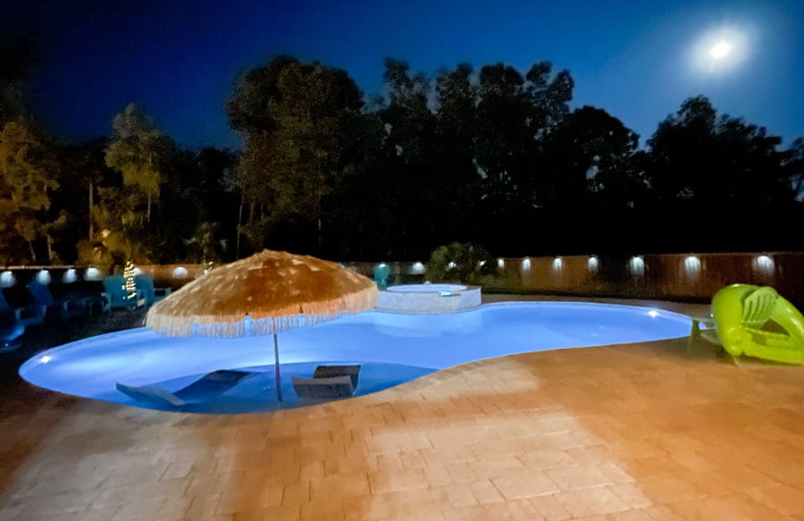 illuminated-pool-at-night-with-thatch-umbrella