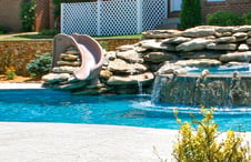 deck-mount-slide-installed-into-rock-waterfall-on-pool