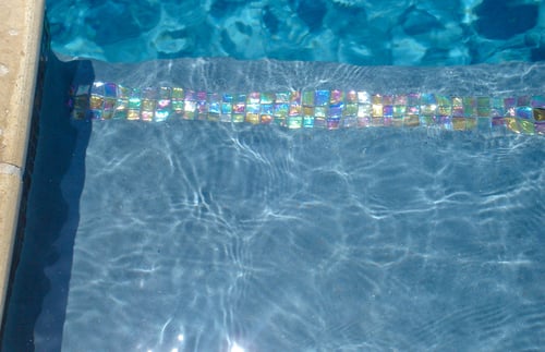 Iridescent glass tile on pool waterline