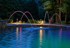 Color-changing LED laminars glowing pink and white over a swimming pool at night