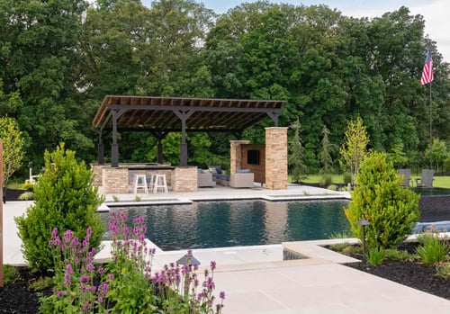 Luxury inground pool with pergola, outdoor kitchen, fireplace, and professional landscaping for backyard entertaining.