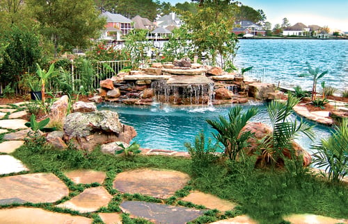Freeform tropical pool surrounded by palm trees and layered tropical landscaping