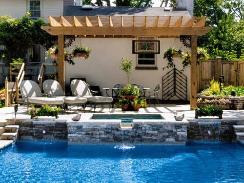Wood pergola with hanging planters over a poolside patio and spa