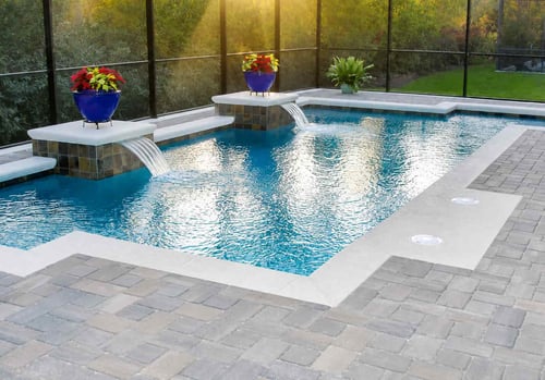 Two sheer descent cascade water features on raised tile pedestals in a screened rectangular pool