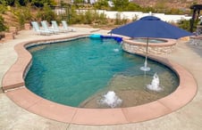 two-fountains-and-umbrella-on-large-swimming-pool-sun-ledge
