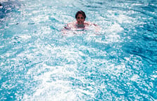 woman-swimming-against-pool-jet